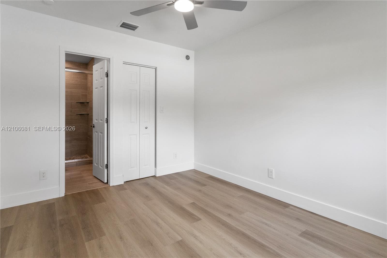 Room featuring wood-finish flooring, a ceiling fan with integrated lighting, and a bi-fold closet door