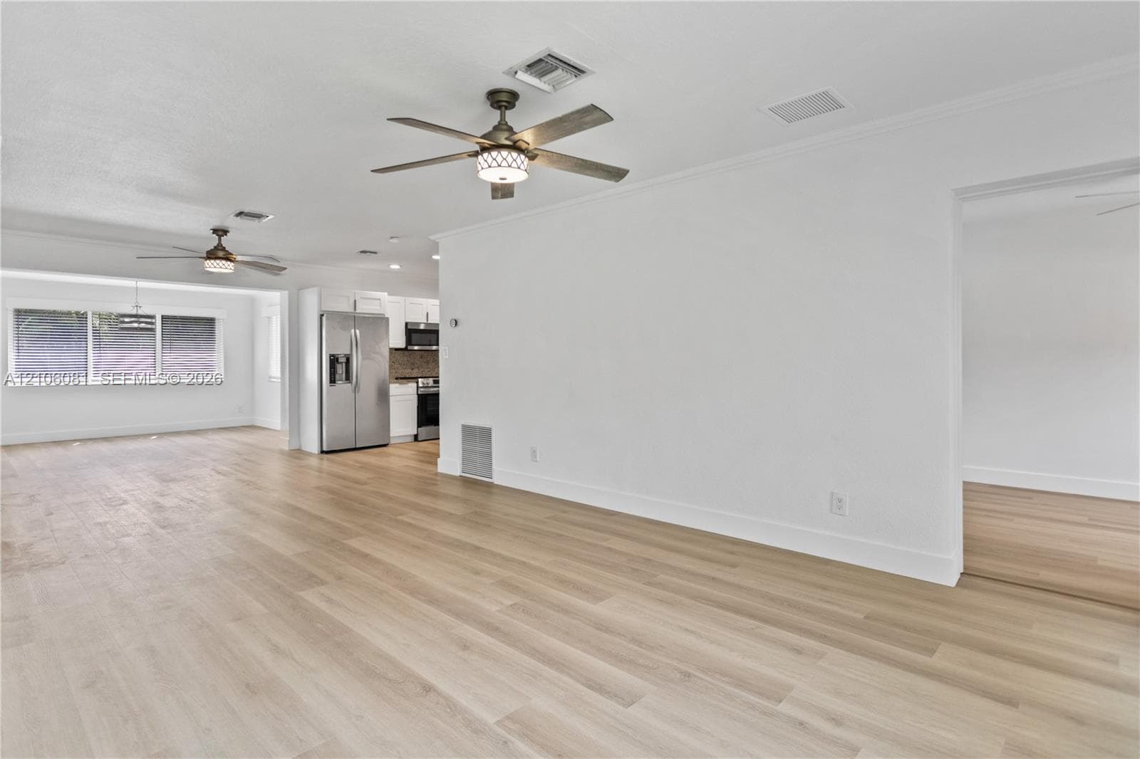 Wood-finish flooring, dual ceiling fans with integrated lighting, and stainless steel kitchen appliances