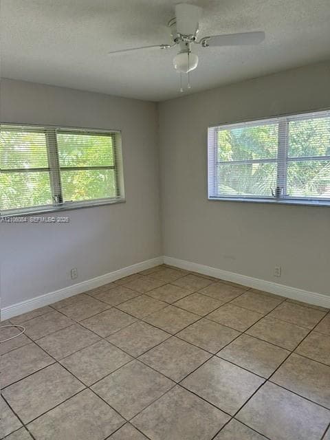 Room featuring tile flooring, neutral wall paint, two windows with blinds, and a ceiling fan