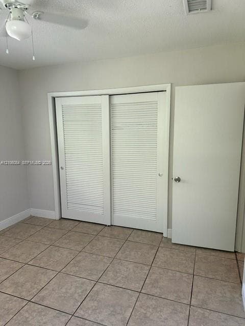 Ceramic tile flooring, white louvered sliding closet doors, and ceiling-mounted light fixture with fan