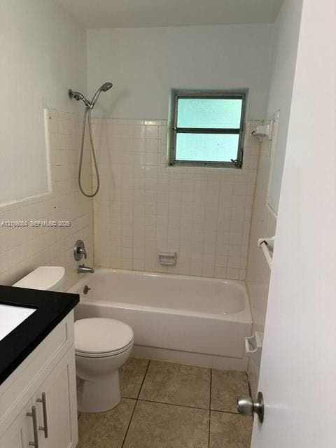 Bathroom featuring a shower and tub combination with wall-surround tiling, a vanity with a dark countertop and white cabinetry, and tile flooring