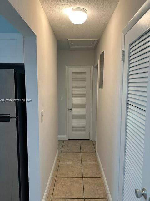 Hallway featuring tile flooring, ceiling-mounted lighting, and louvered-style interior doors