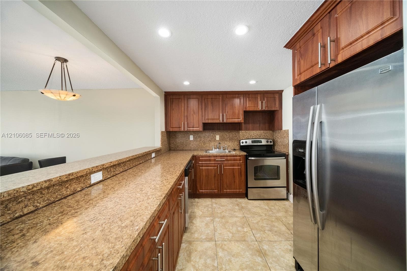 Kitchen featuring wood cabinetry, stone-finish countertops, stainless steel appliances, tile flooring, and recessed lighting