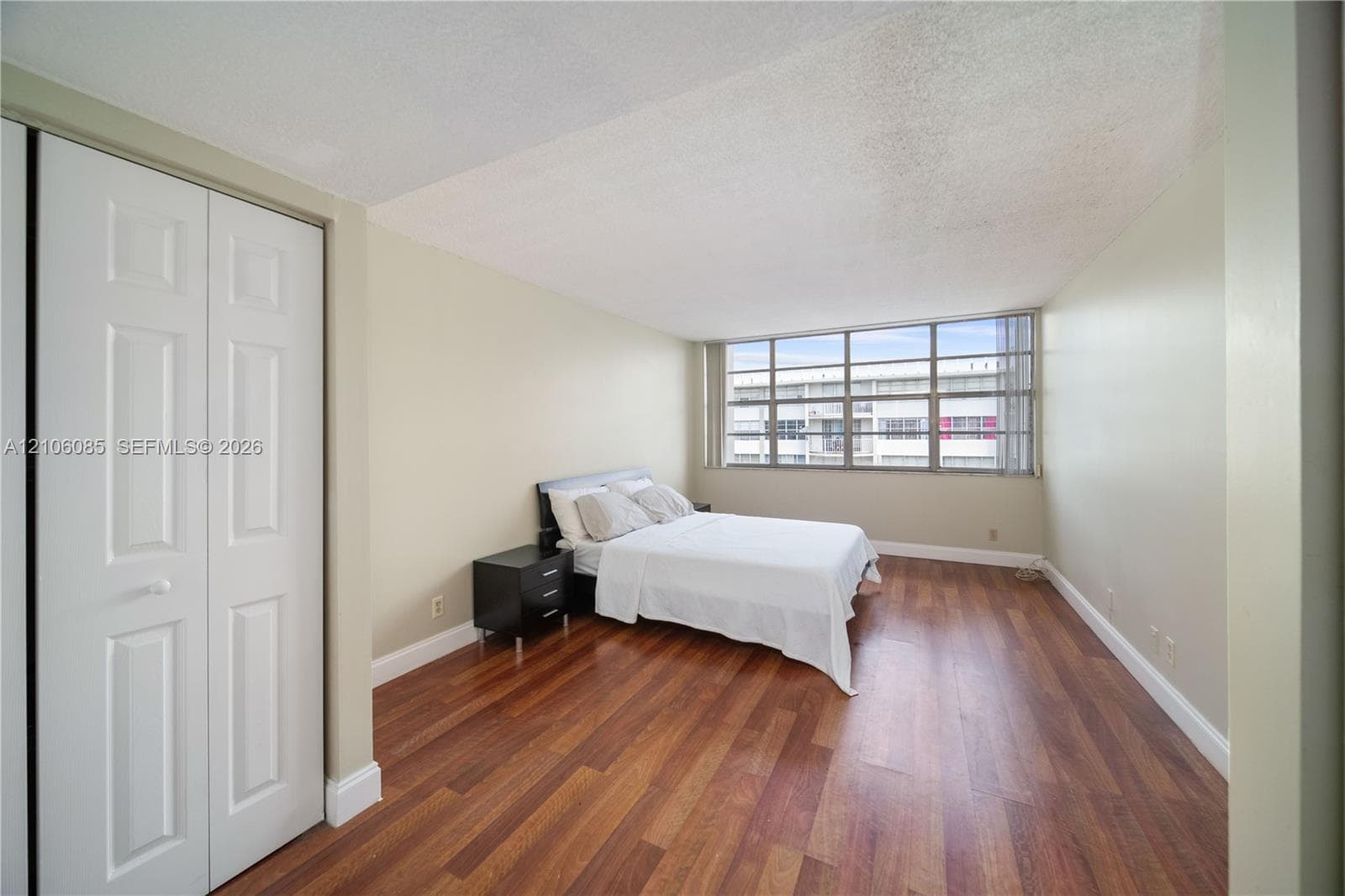 Room featuring wood-finish flooring, floor-to-ceiling multi-pane windows, and a built-in double-door closet