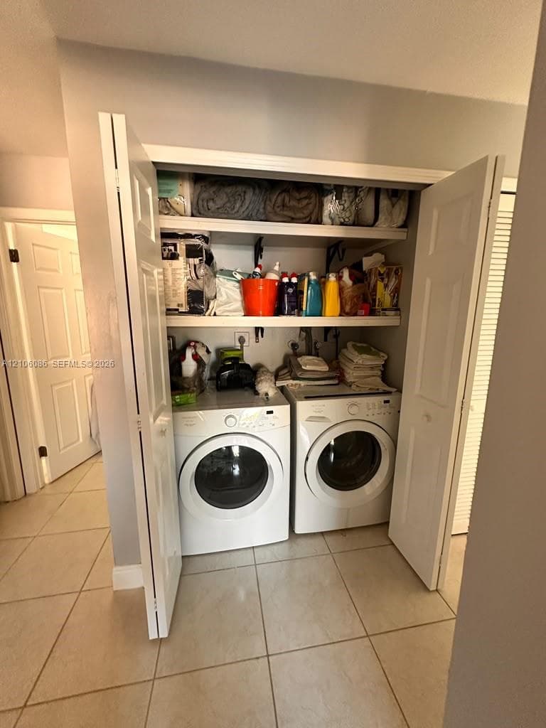 Laundry closet featuring two levels of built-in shelving, tile flooring, and bi-fold doors