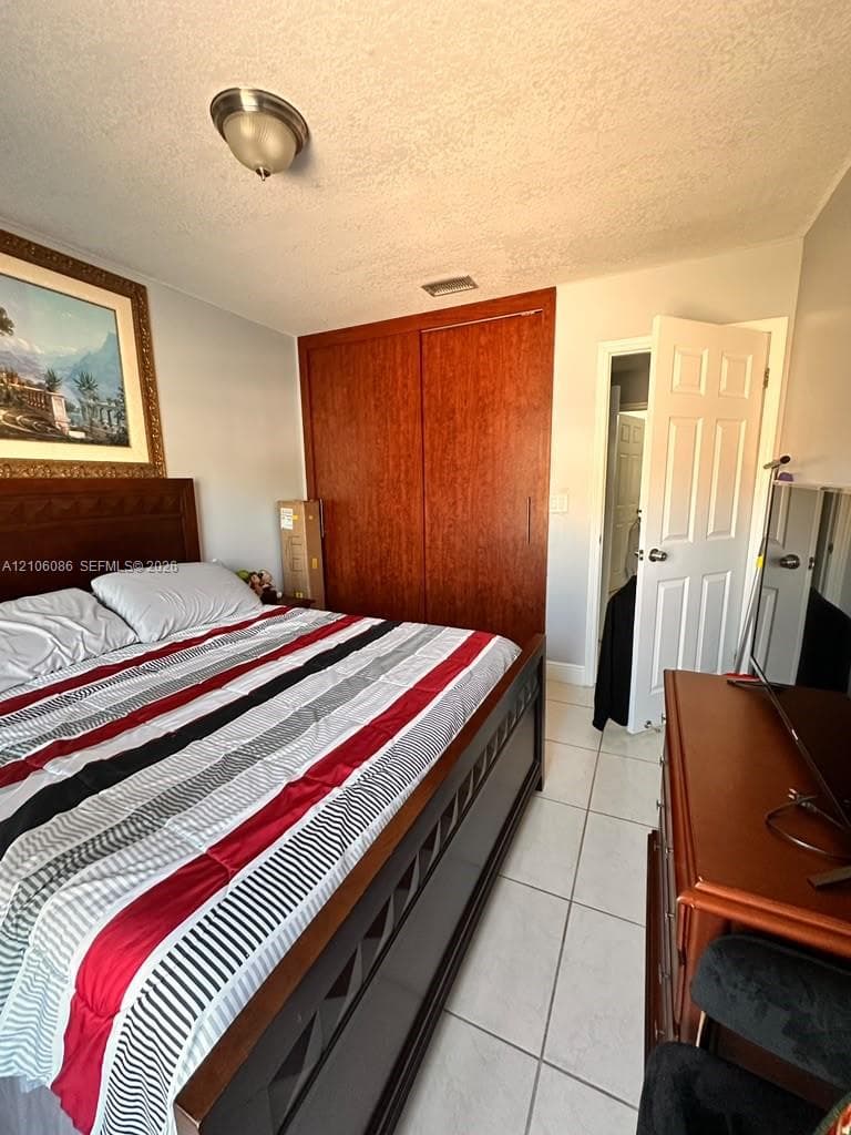 Room featuring tile flooring, wood-finish sliding closet doors, and a flush-mount ceiling light fixture