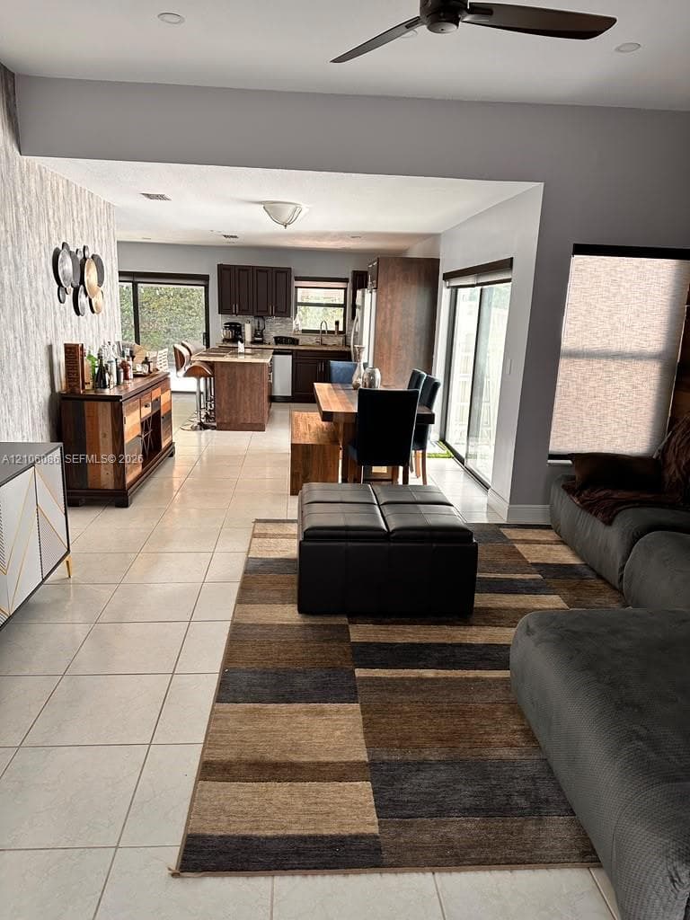 Open-concept interior featuring large-format tile flooring, recessed lighting, ceiling fan, and sliding glass doors