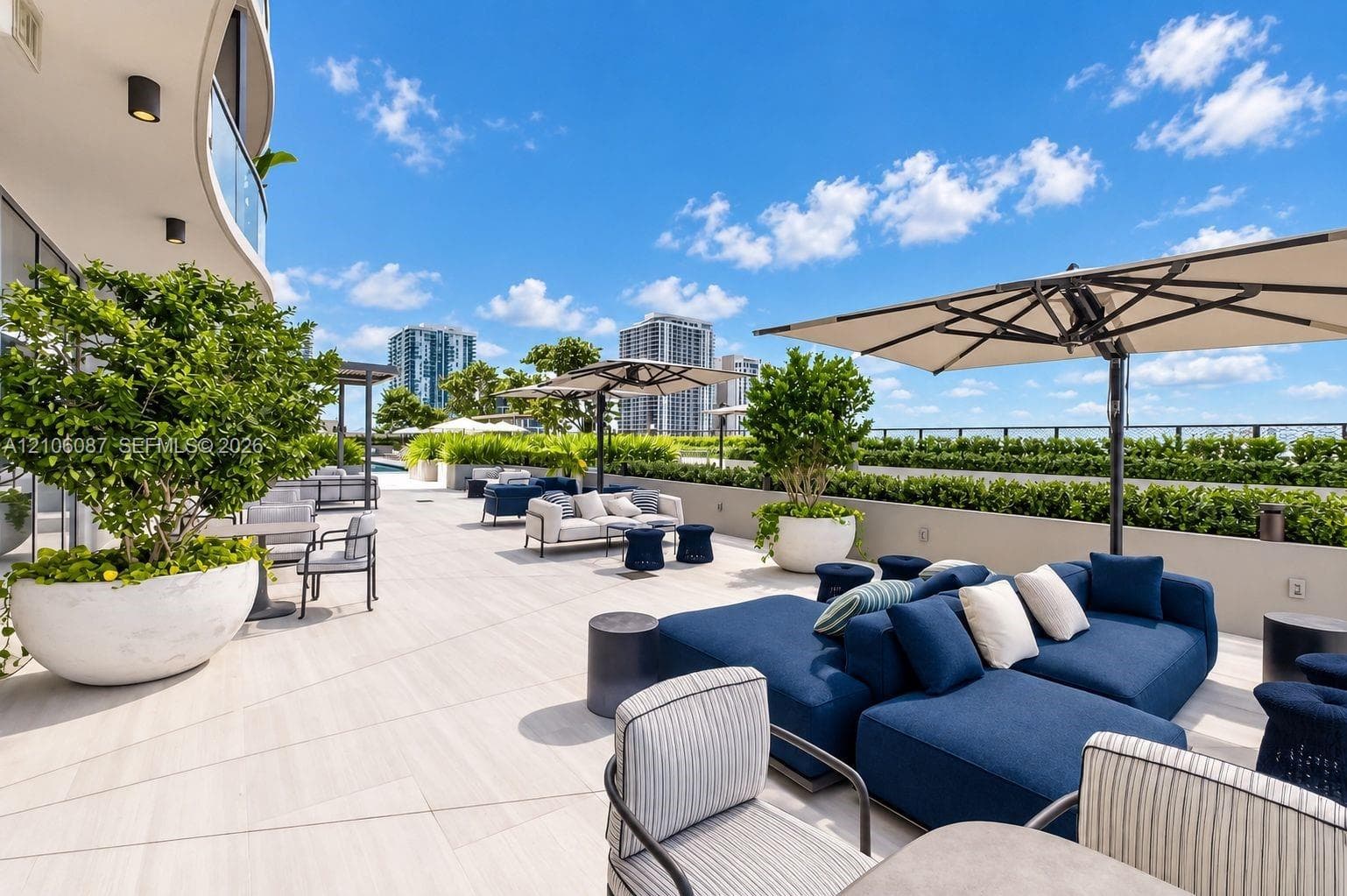 Expansive rooftop terrace featuring large-format stone-finish flooring, integrated perimeter landscaping, and elevated masonry wall enclosures