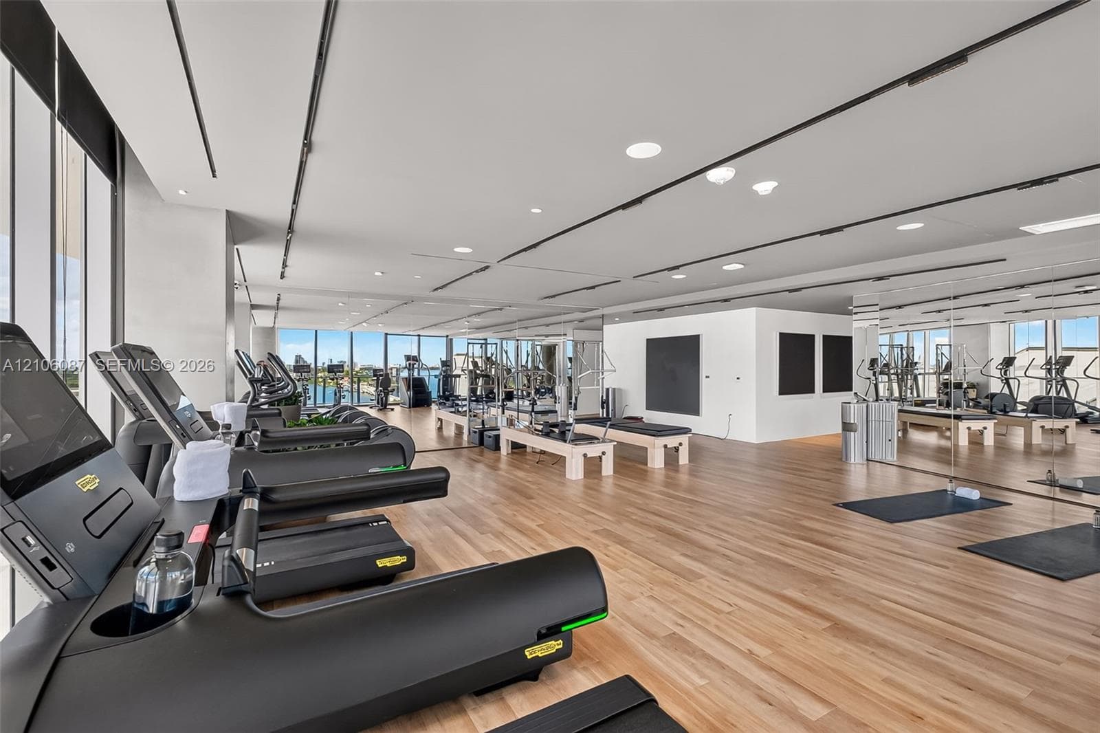 Fitness center featuring floor-to-ceiling windows, wood-finish flooring, full-wall mirrors, and recessed ceiling lighting