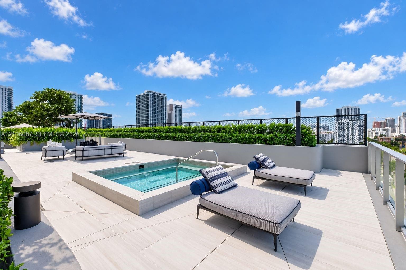 Rooftop terrace featuring a built-in spa, expansive tile decking, a metal railing, and integrated privacy hedging
