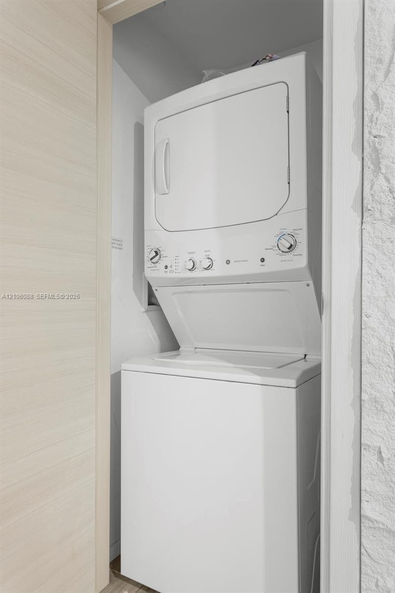 Stacked white laundry center featuring a top-loading washer and front-loading dryer with analog control dials