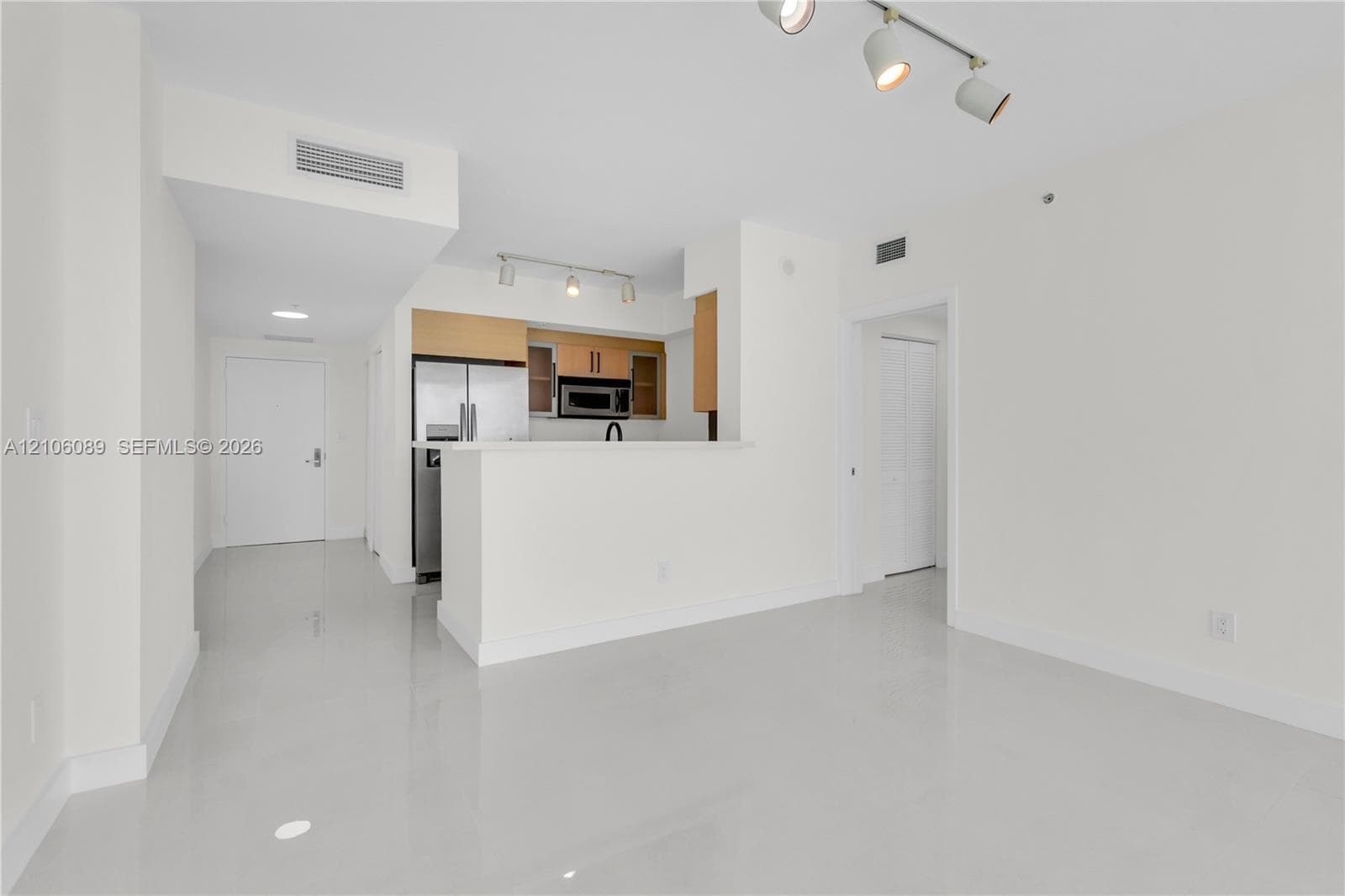 Open-concept kitchen featuring light wood cabinetry, stainless steel appliances, a peninsula counter, and polished tile flooring