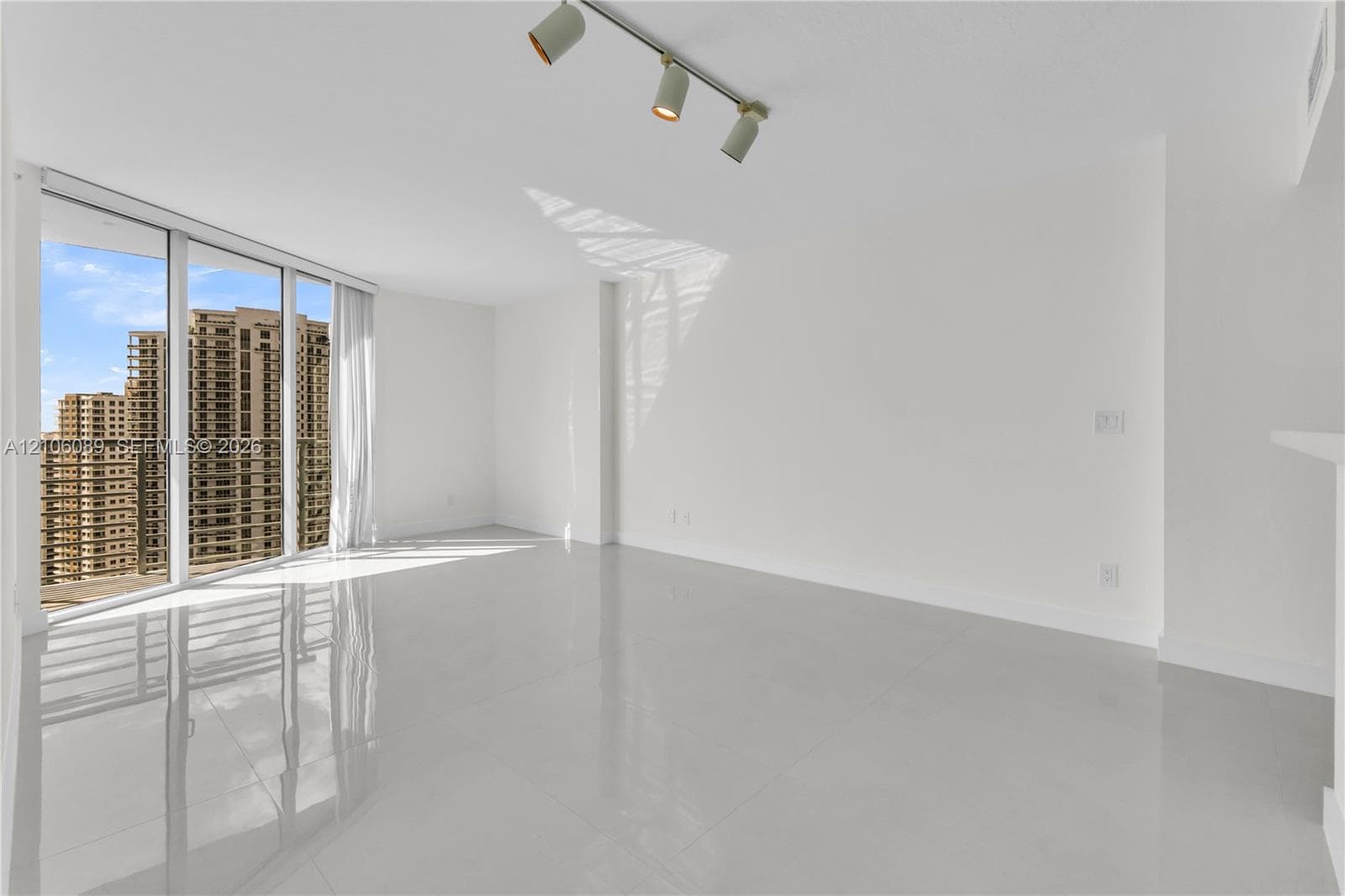 Interior space featuring polished porcelain flooring, floor-to-ceiling glass wall, triple-head track lighting, and a private balcony