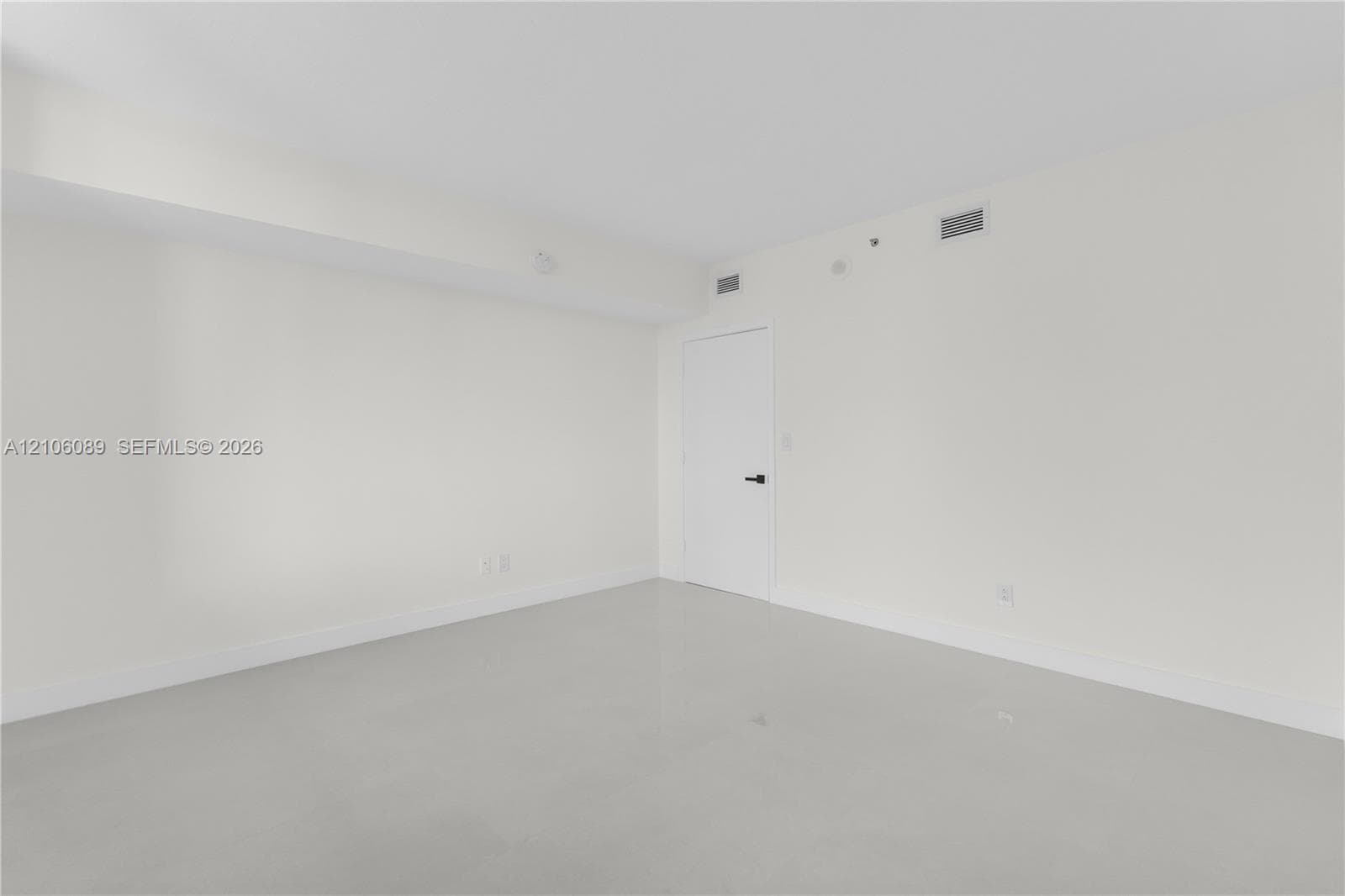 Neutral wall finishes, smooth-finish ceiling, solid-core door with matte black hardware, and polished hard-surface flooring
