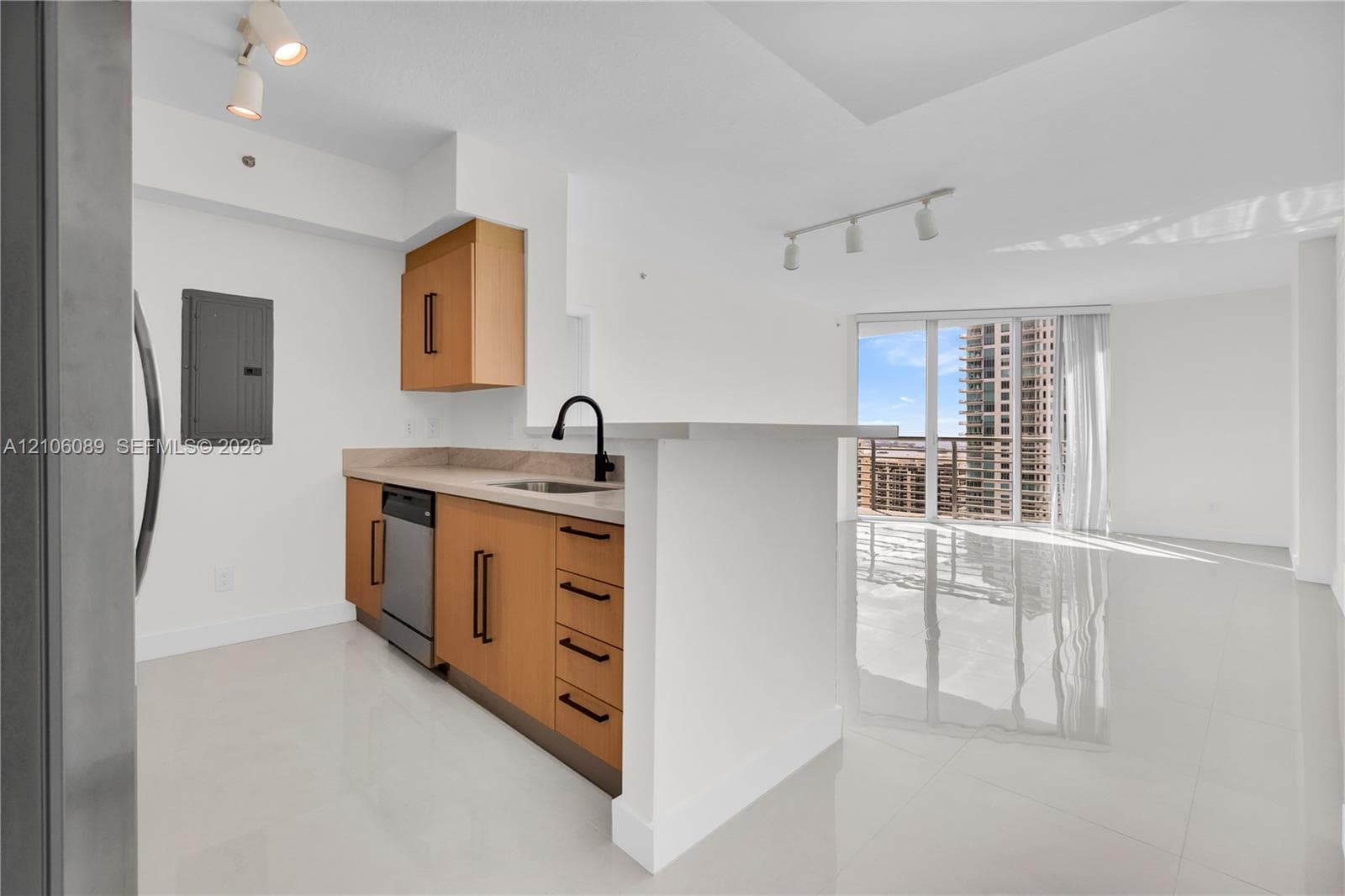 Kitchen featuring light wood-finish cabinetry, matte black hardware, stone-finish countertops, stainless steel dishwasher, and a peninsula with a matte black faucet