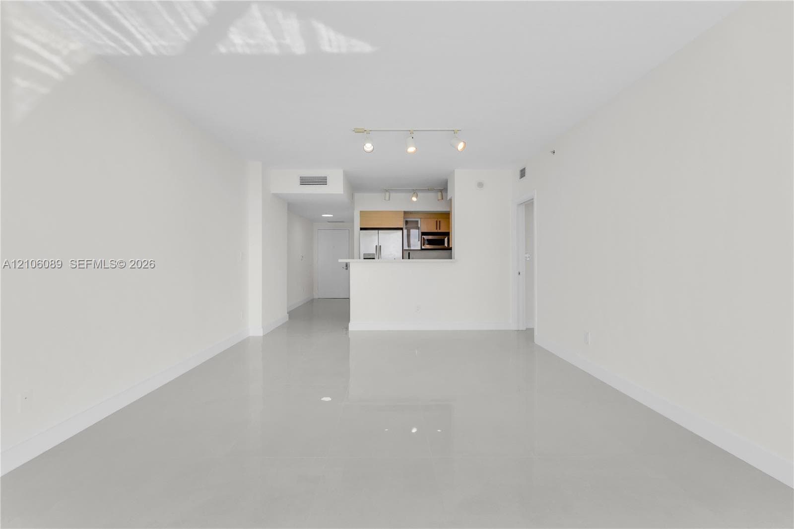 Open-concept interior featuring light-toned tile flooring, recessed track lighting, and a kitchen breakfast bar