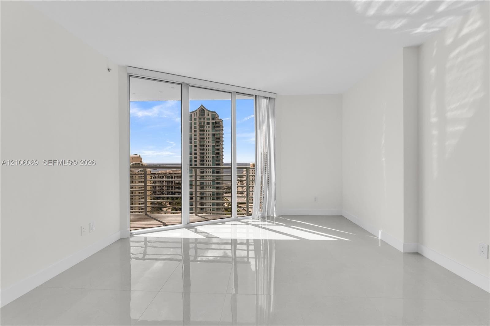 Floor-to-ceiling glass windows, private balcony with metal railing, and polished tile flooring