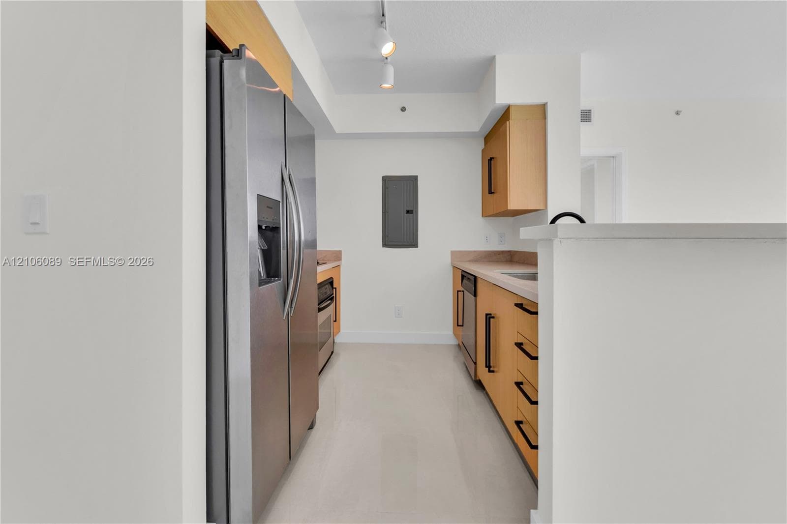 Kitchen featuring light-tone wood cabinetry, stainless steel side-by-side refrigerator, stone countertops, track lighting, and tile flooring