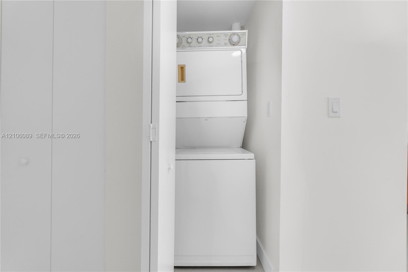 Laundry closet featuring a built-in stacked washer and dryer unit behind dual bi-fold doors