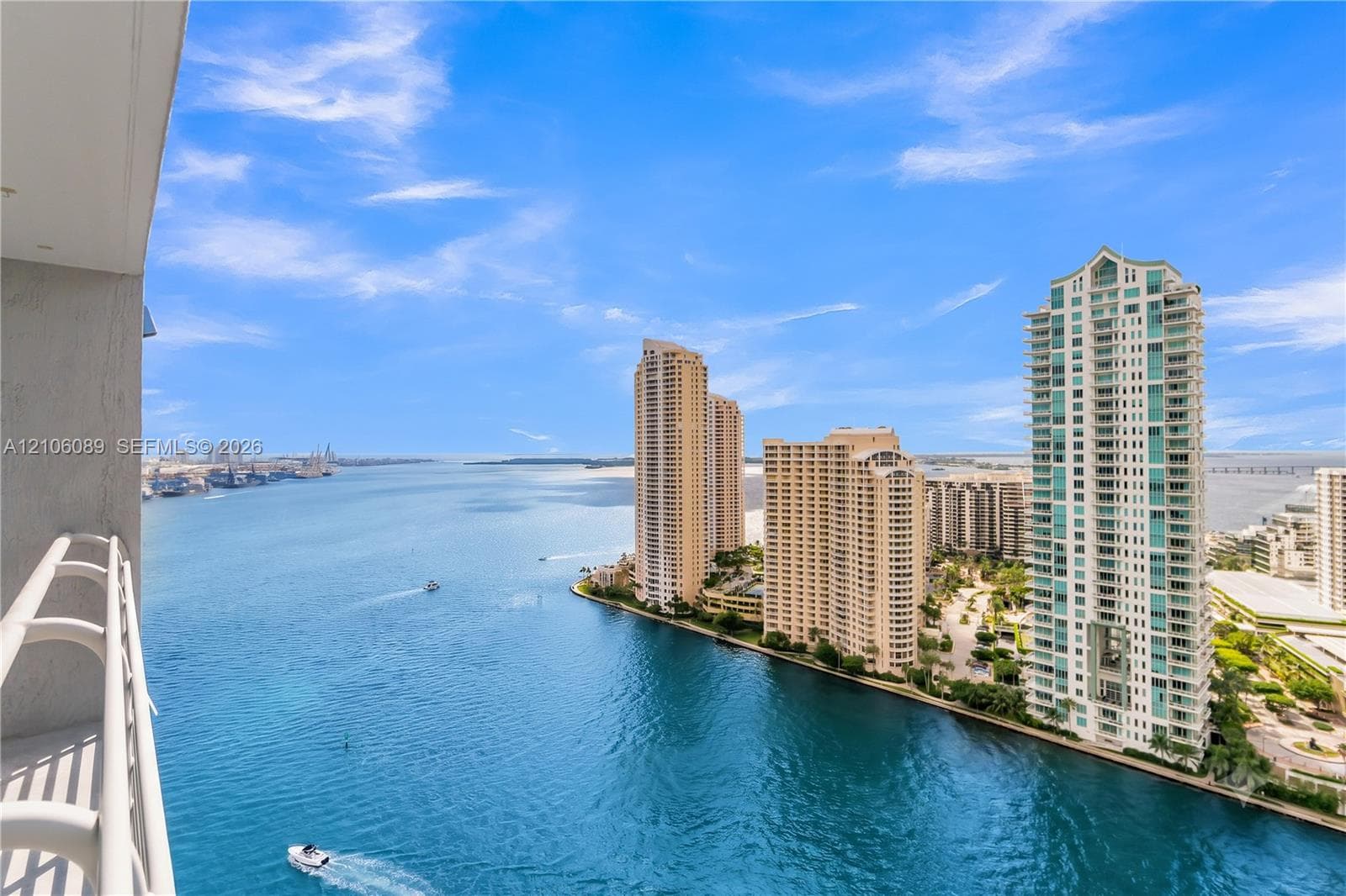 Private balcony featuring white metal railings and expansive water and urban skyline backdrop