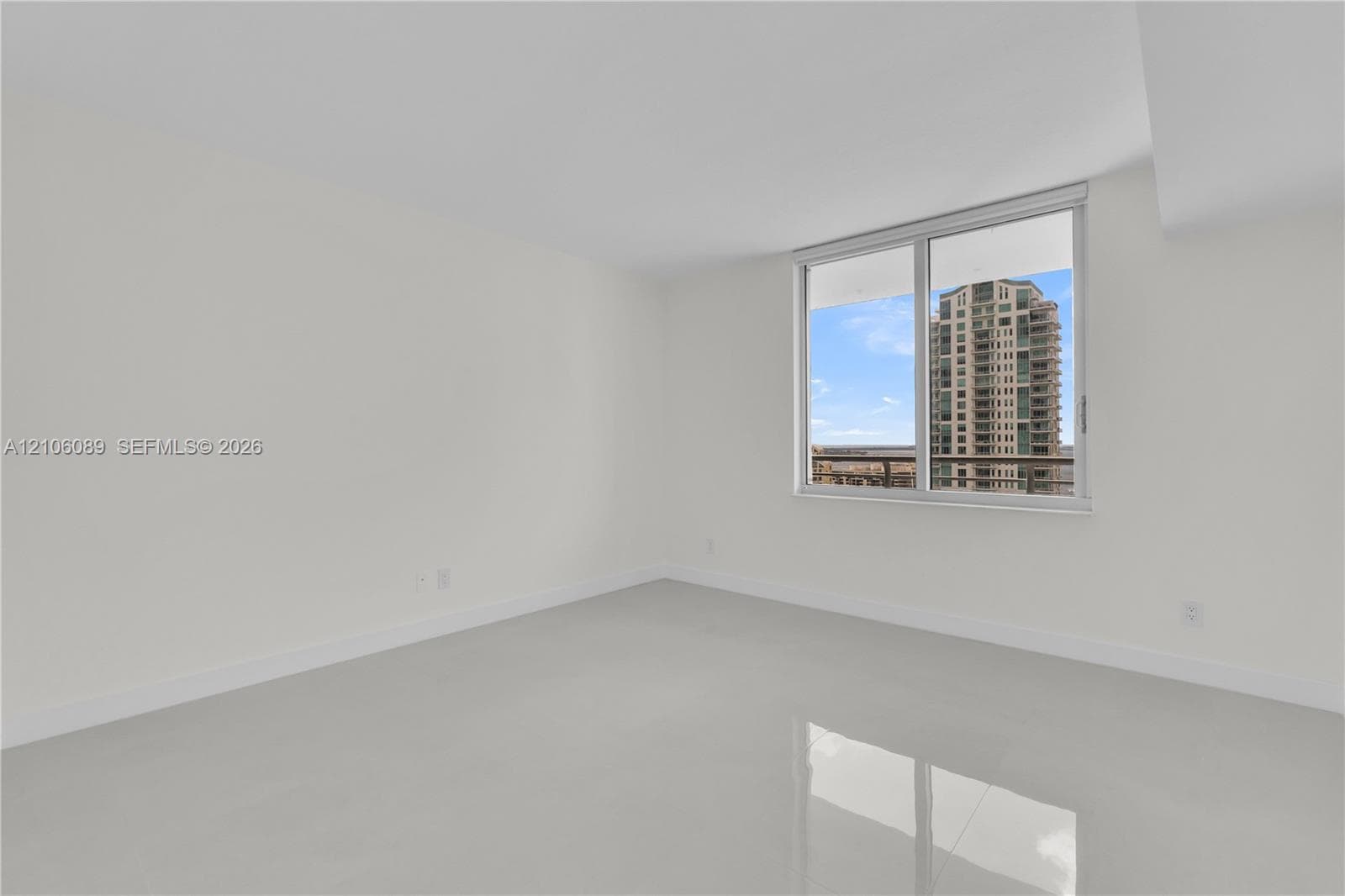 Room with neutral walls, polished tile flooring, and large sliding glass window