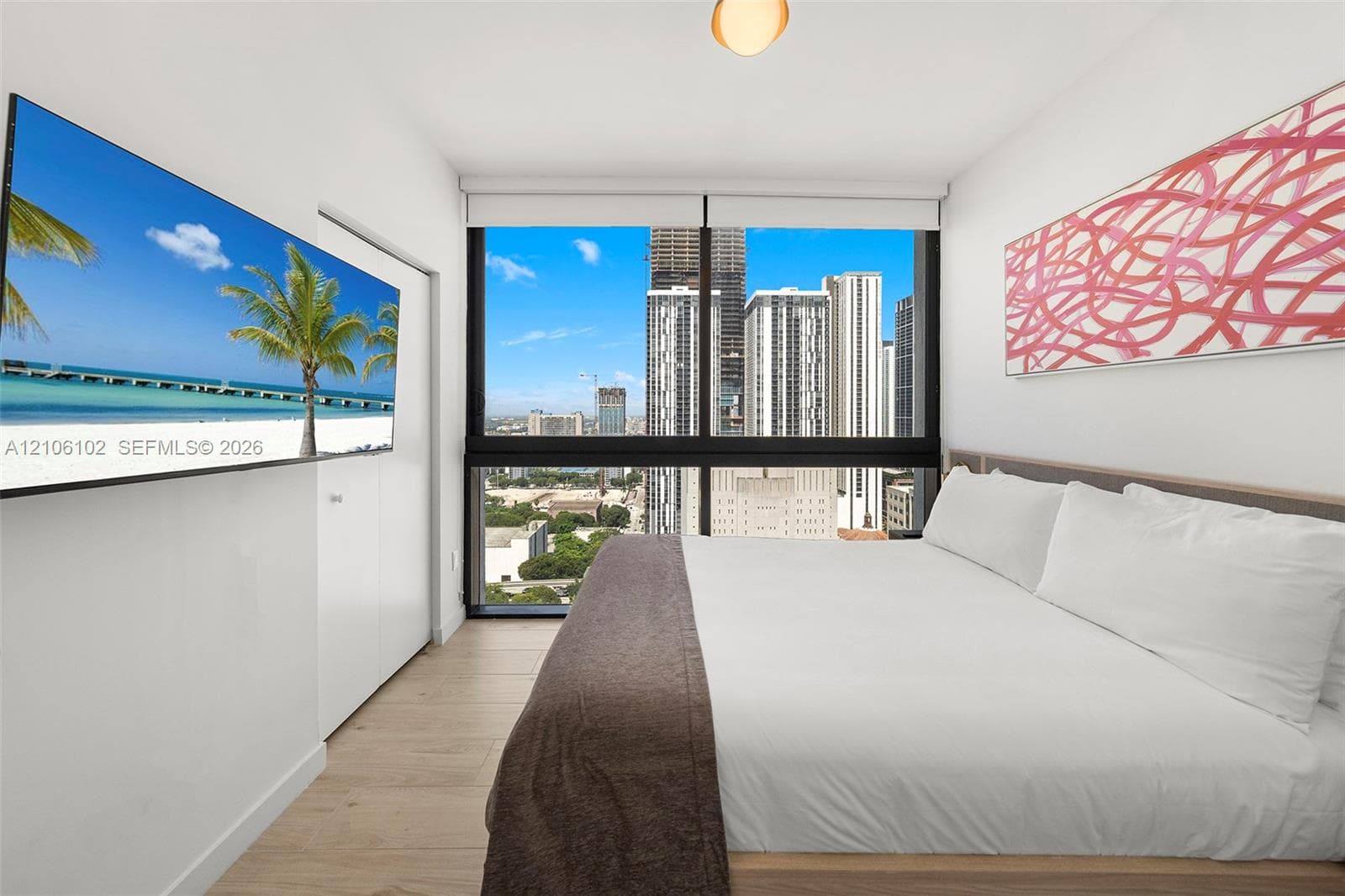 Floor-to-ceiling windows featuring urban scenery, wood-finish flooring, and white interior finishes
