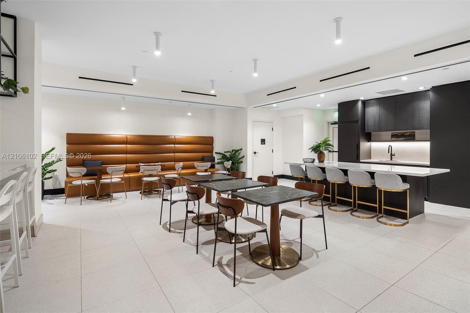 Large common room featuring tile flooring, recessed ceiling lighting, a built-in upholstered wall bench, and a kitchenette with quartz countertops and dark cabinetry