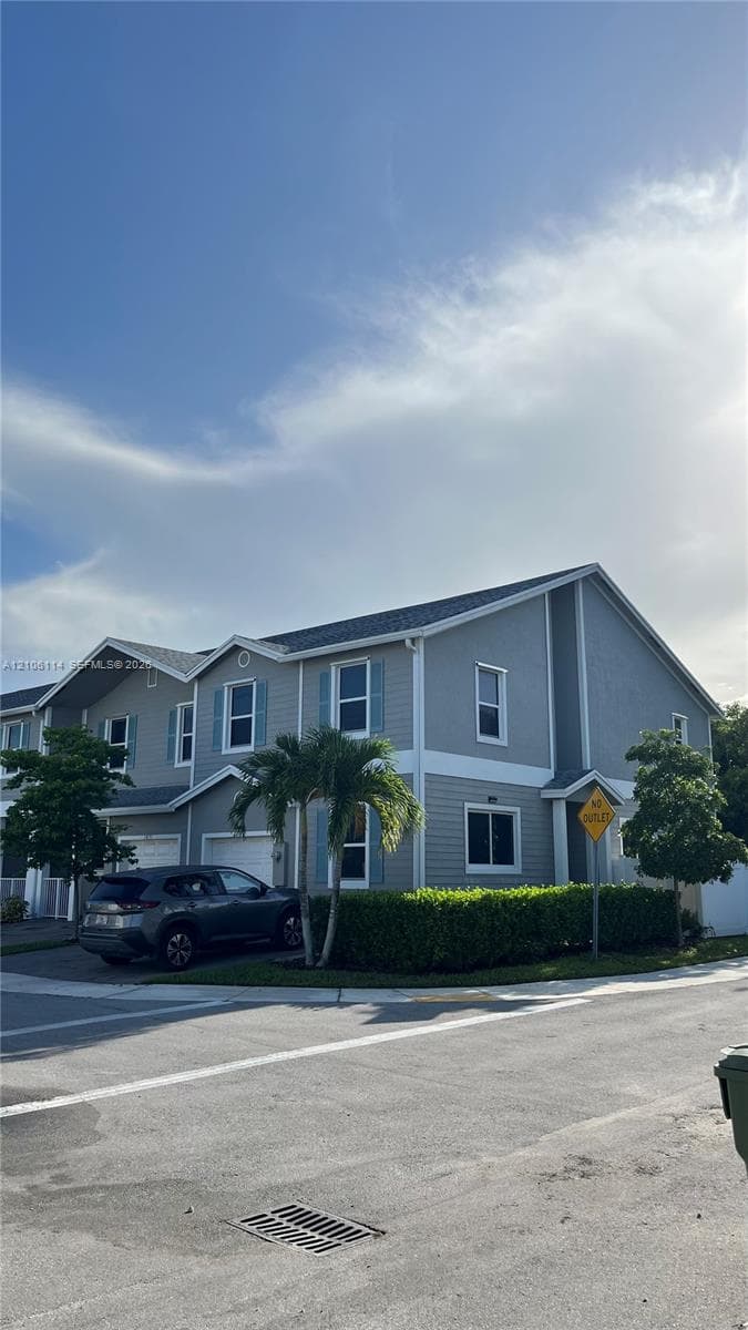 Two-story exterior featuring grey siding, white trim, decorative window shutters, an asphalt shingle roof, and an attached garage
