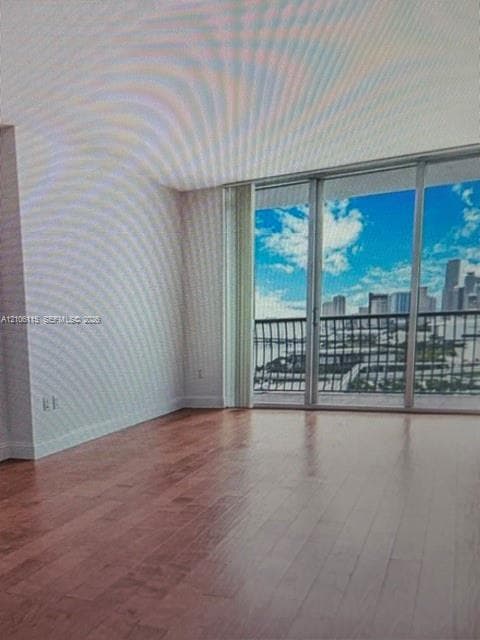 Living space featuring wood-finish flooring, floor-to-ceiling sliding glass doors, and a private balcony with metal railing