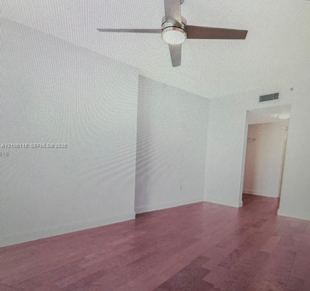 Wood-finish flooring, brushed metal ceiling fan with integrated light fixture, and recessed wall area