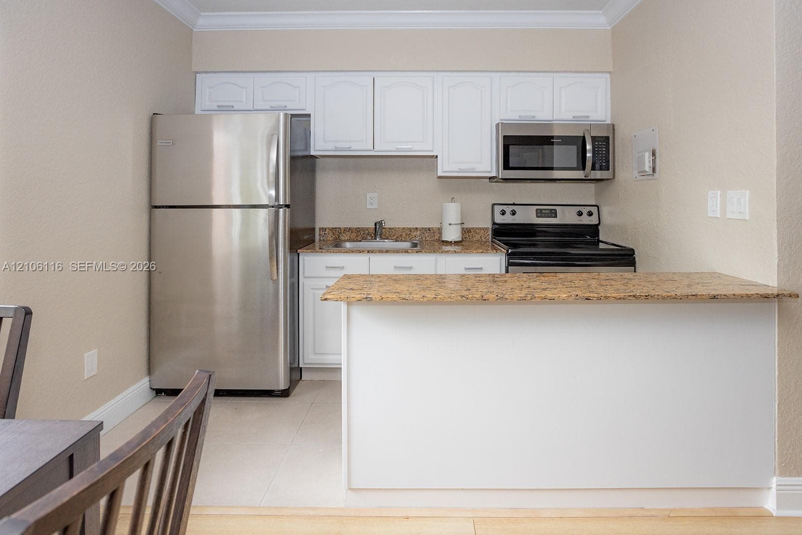 Kitchen featuring white cabinetry, stone-surface countertops, and stainless steel appliances including a refrigerator, microwave, and electric range