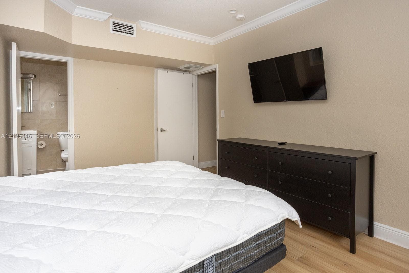 Room featuring wood-finish flooring, crown molding, and neutral wall paint