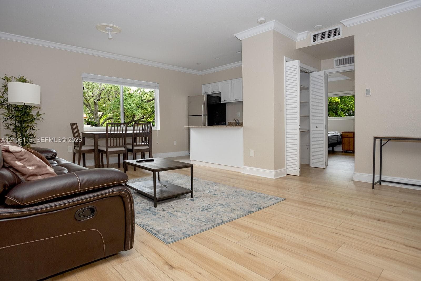 Light-filled interior featuring wood-finish flooring, crown molding, stainless steel kitchen appliances, and louvered-door closet cabinetry