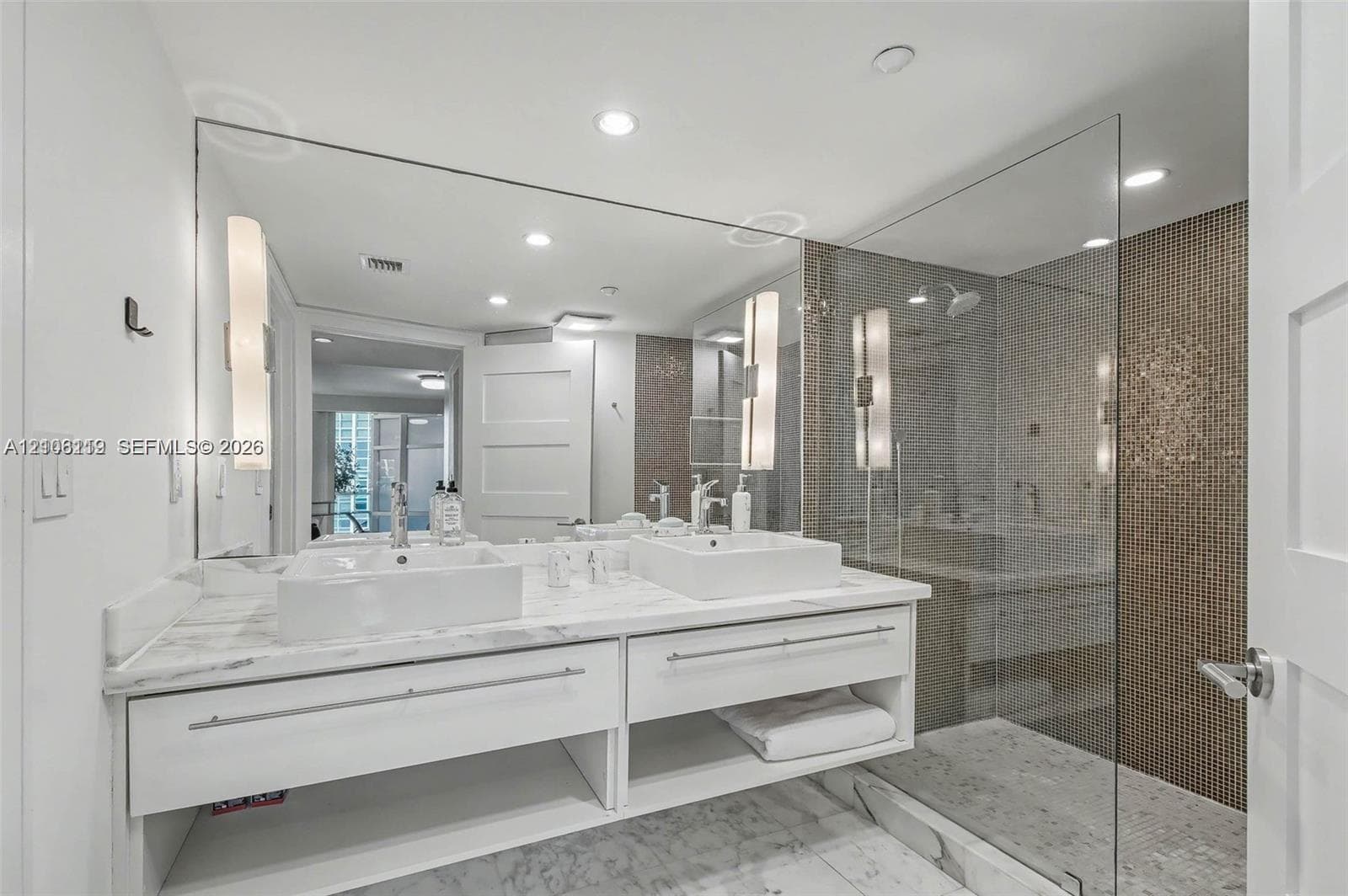Floor-to-ceiling built-in cabinetry, large window, flush-mount ceiling lighting, and neutral stone-finish flooring