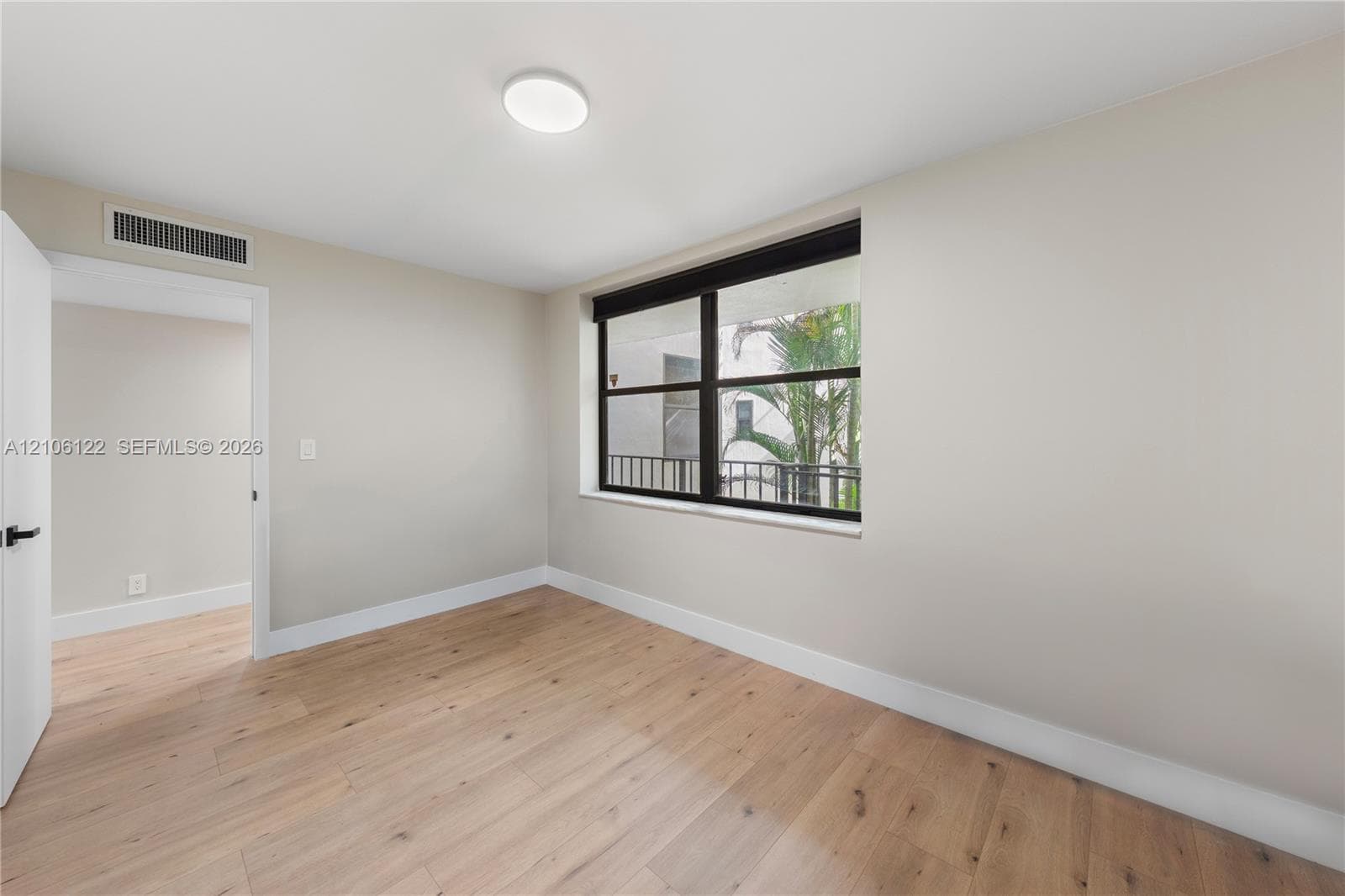 Room featuring wood-finish flooring, neutral wall paint, and a multi-pane window with a black frame