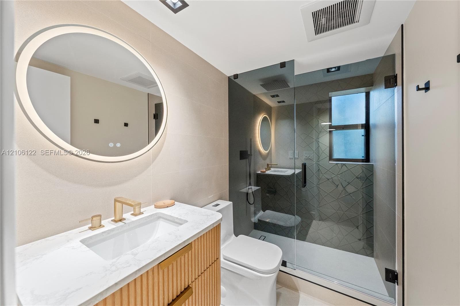 Floating wood-finish vanity with a stone countertop, integrated rectangular sink, and gold-tone hardware
