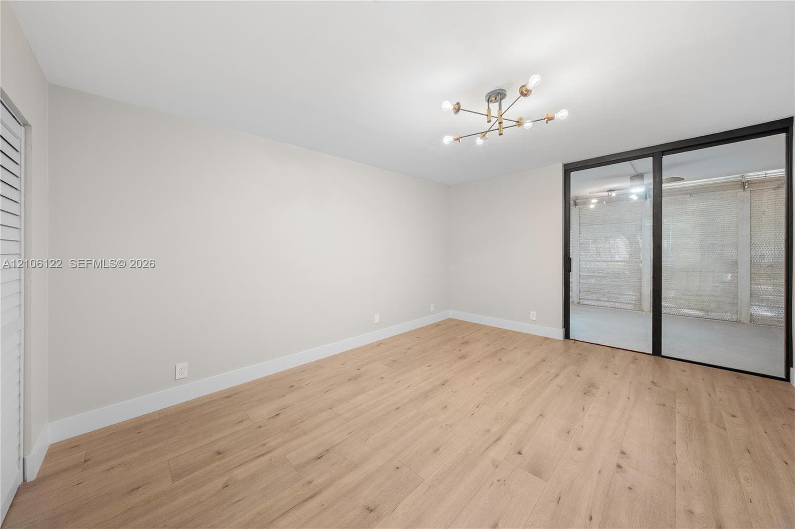 Wood-finish flooring, modern multi-arm light fixture, and black-framed sliding glass doors
