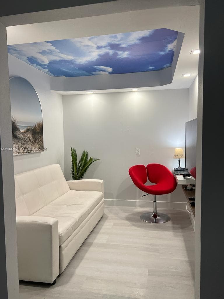 Interior room featuring a tray ceiling with a recessed mural, wood-finish flooring, and integrated recessed lighting