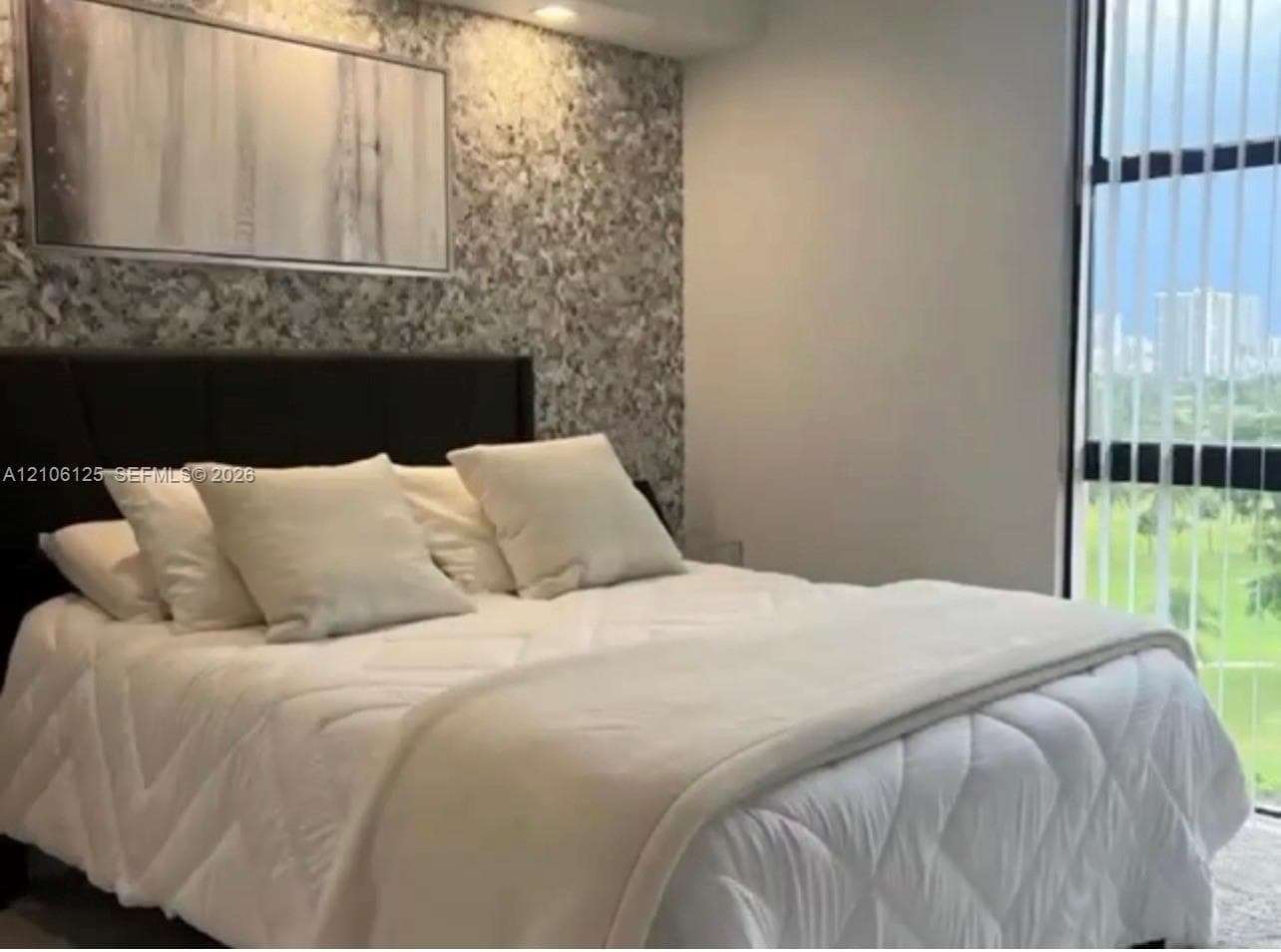 Textured accent wall featuring metallic finishes, recessed ceiling lighting, and floor-to-ceiling windows