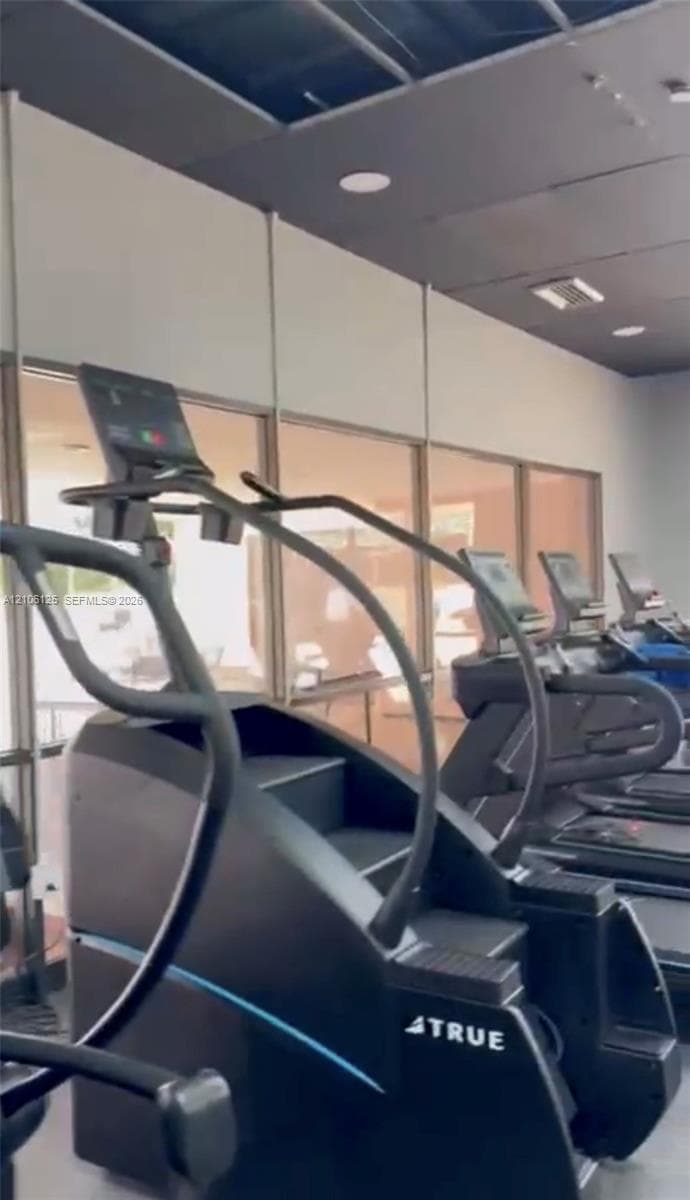 Fitness center featuring floor-to-ceiling glass windows, recessed ceiling lighting, and a dark-toned ceiling finish