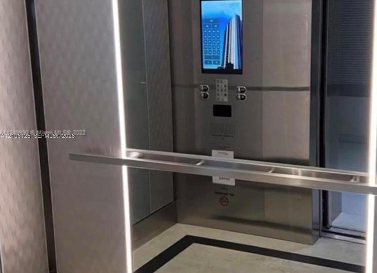 Private elevator interior featuring a stainless steel control panel, integrated touch-screen interface, full-length handrail, vertical LED lighting accents, and geometric-patterned wall panels