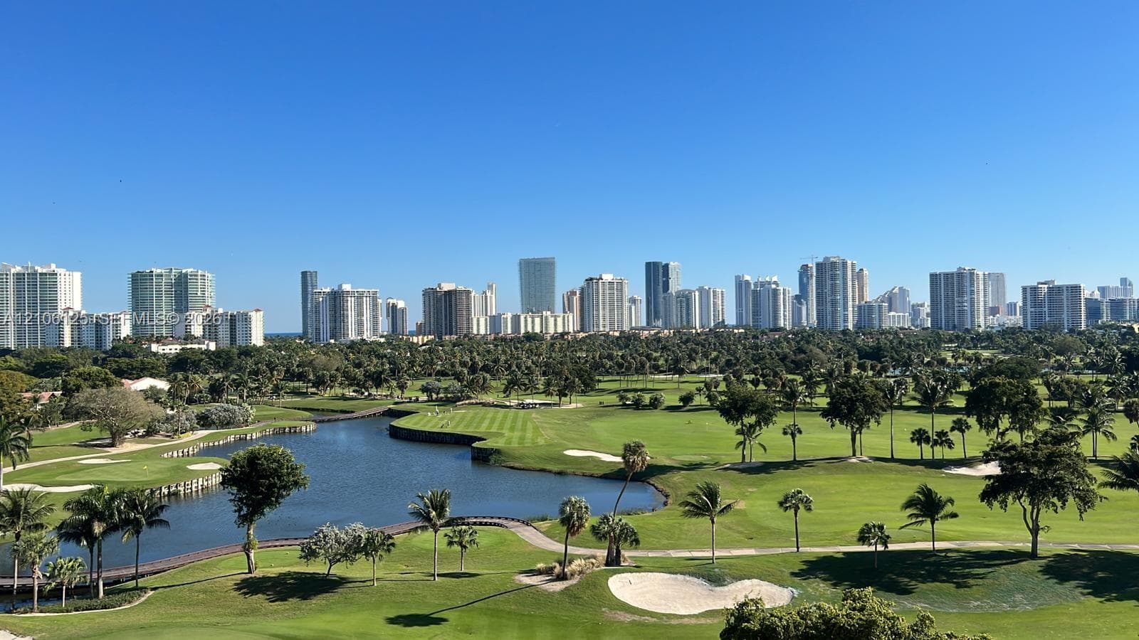 Panoramic golf course and water feature scenery with a backdrop of the urban skyline