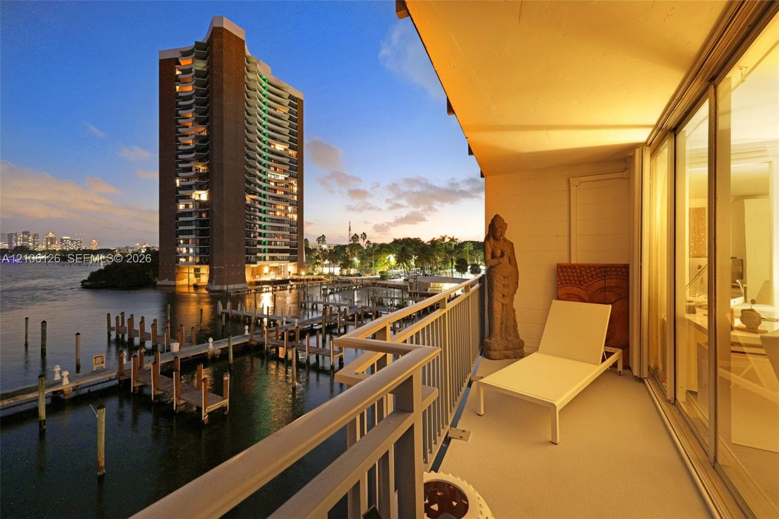 Covered balcony featuring white metal railings, smooth concrete flooring, and full-height sliding glass doors