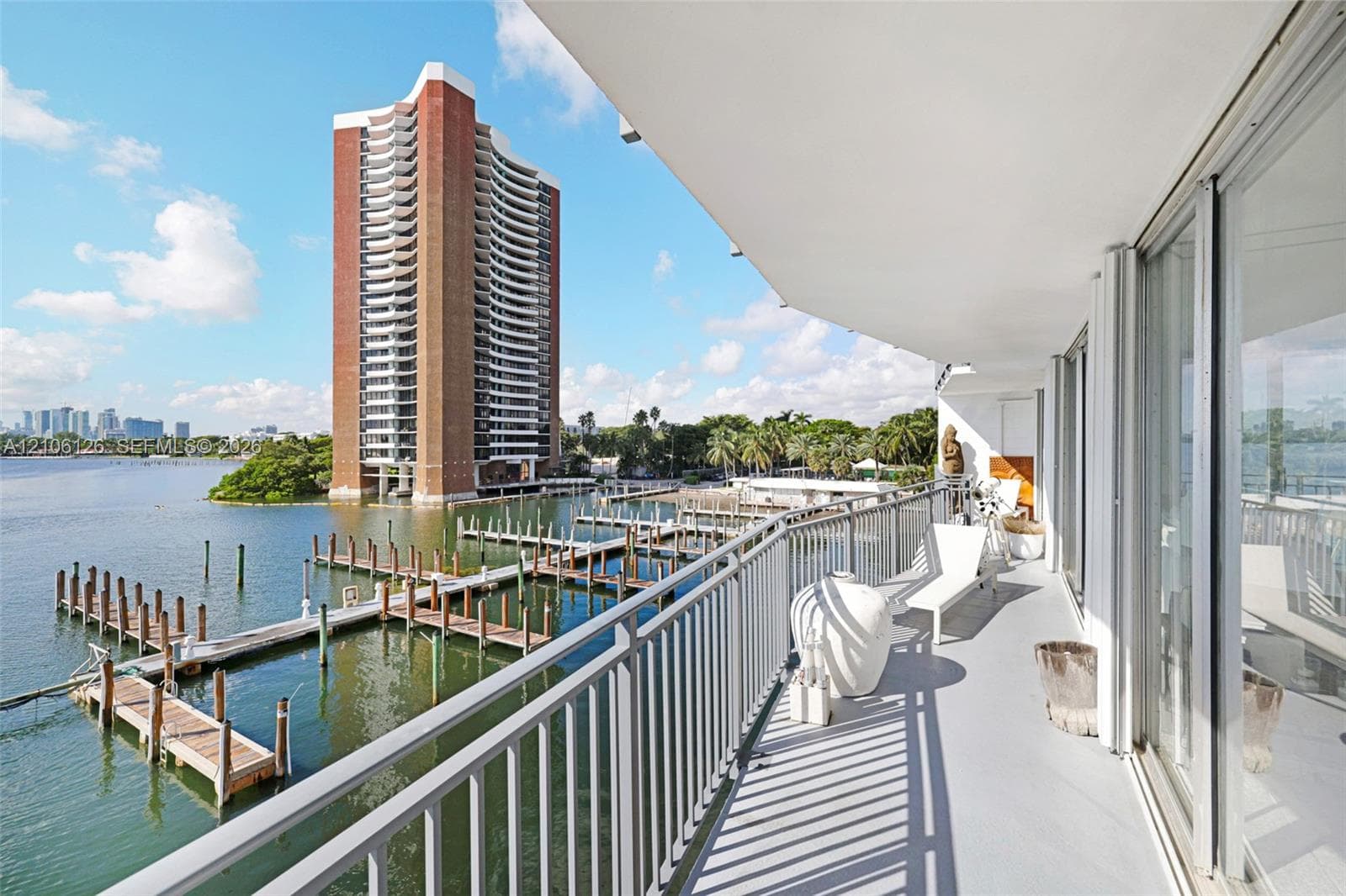 Covered balcony featuring metal railings, smooth surface flooring, and floor-to-ceiling glass sliding doors