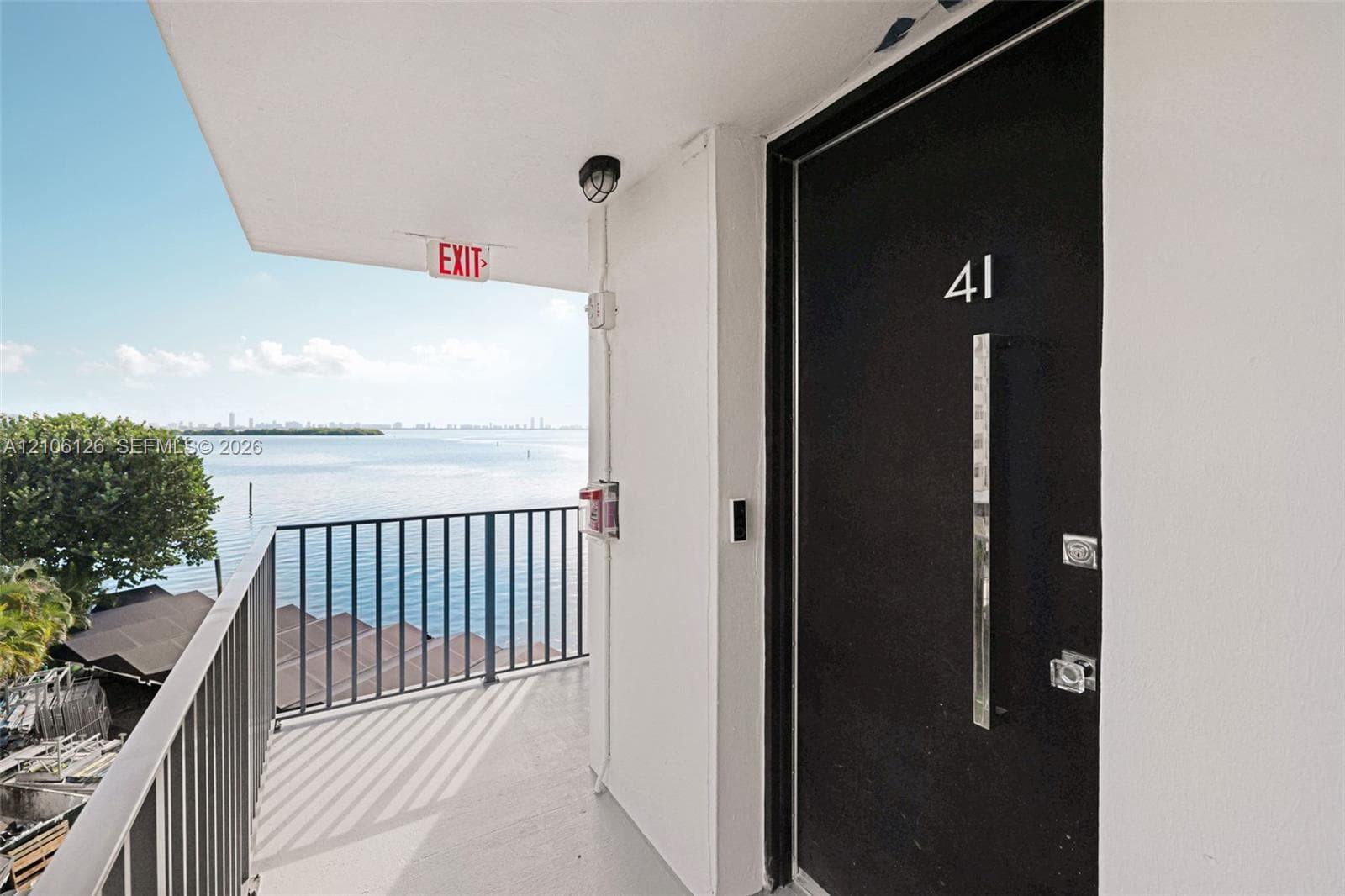 Entrance featuring a black door with a vertical metallic handle and metal railing overlooking the water