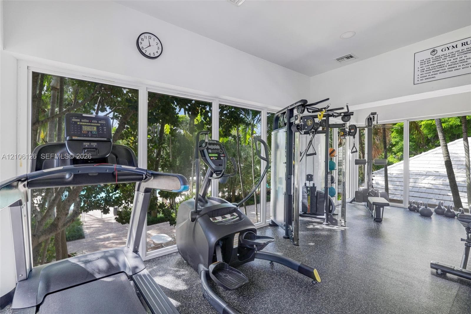 Floor-to-ceiling glass wall panels with expansive exterior foliage and rubberized flooring