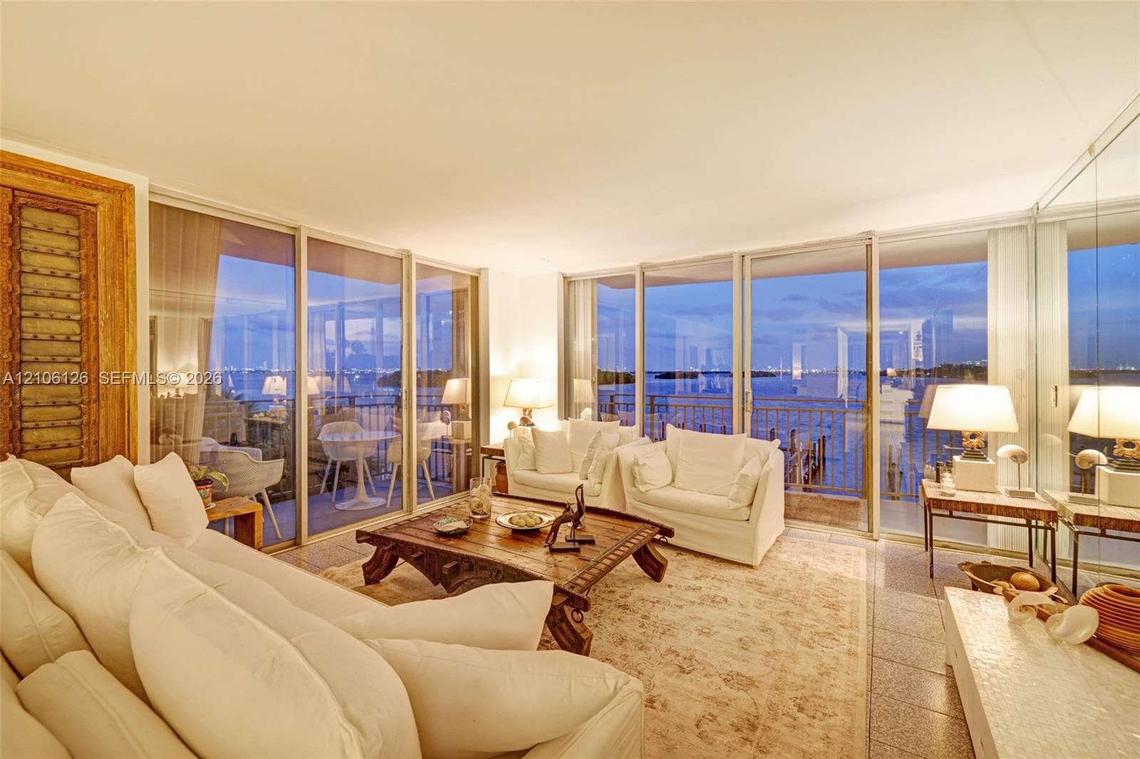 Floor-to-ceiling glass sliding doors, stone tile flooring, mirrored wall paneling, and an expansive exterior balcony