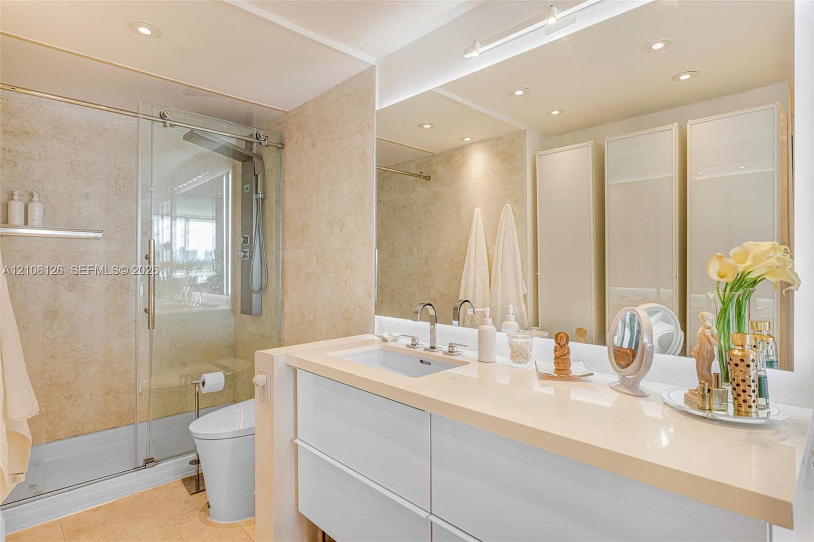Dual-sink vanity with rectangular undermount basins, stone-finish countertop, polished chrome widespread faucets, and large-format wall-to-wall mirror with recessed ceiling lighting