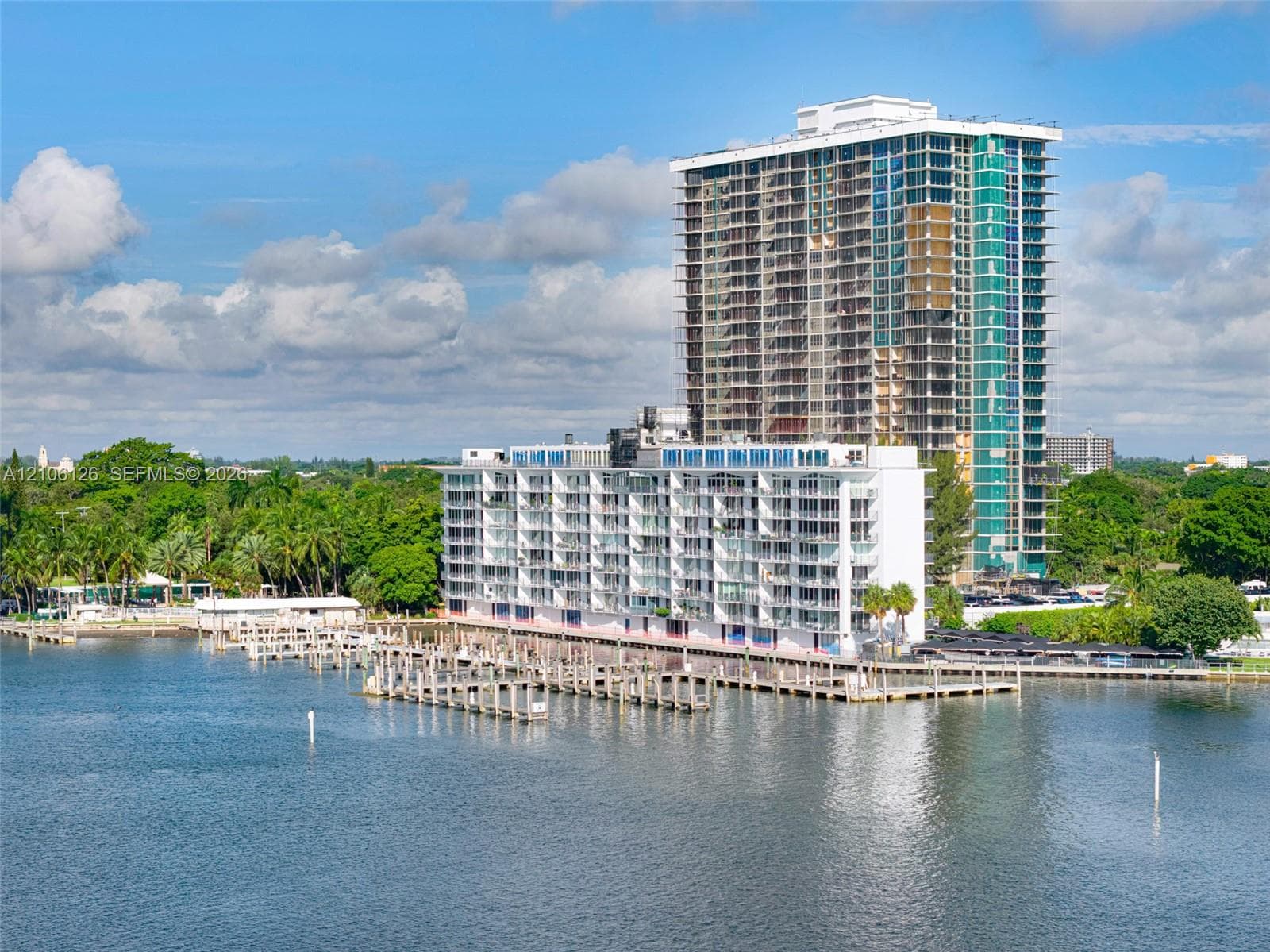 High-rise residential building featuring floor-to-ceiling glass paneling, wraparound balconies, and an extensive private deep-water dock system
