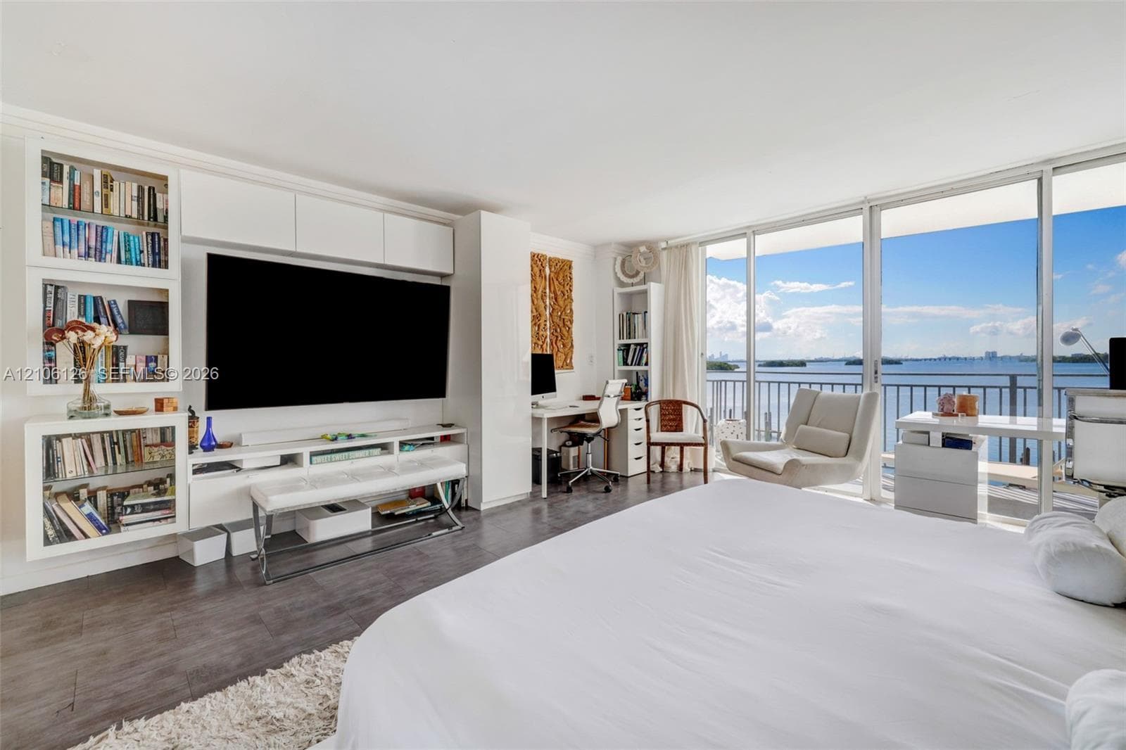 Living space featuring crown molding, wall-mounted air conditioning unit, wood-finish flooring, and mirrored closet doors